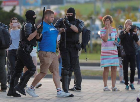 اثنان من قوات انفاذ القانون يعتقلان رجلا خلال مظاهرة في مينسك. تصوير: فاسيلي فيدوسينكو - رويترز.